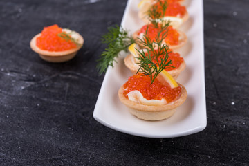 Canapes with salmon red caviar on a black  background