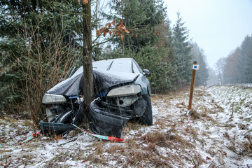 Car destroyed during the traffic accident. It was caused by the bad weather conditions in winter, because of the black ice or snow. The car is abandoned and stands by the road in the snowfall. - obrazy, fototapety, plakaty