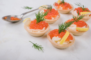 Tartlets with red caviar on white background. Selective focus.