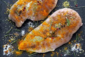 Raw chicken fillet with turmeric and spices marinated on a stone board. Top view. Cooking Curry.