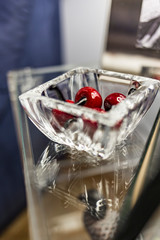 Red cherries fruit on a transparent glass pot with reflection and shape over another transparent glass table
