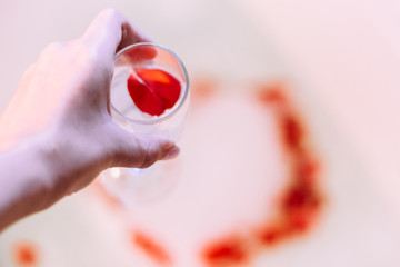 Romantic bath with rose. Bath water with rose petals. St. Valentine's Day bath. Aromatherapy with flower petals.