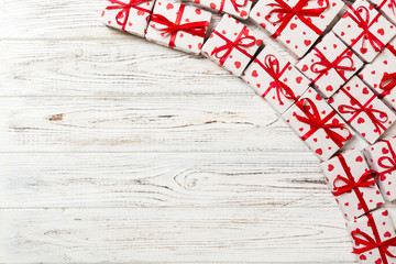 Fototapeta premium valentine or other holidays concept. Lots of Gift boxes on wood background top view. Presents in craft paper decorated with red ribbon bows and heart. top view with copy space for text frame