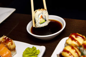 closeup man eating delicious sushi with chopsticks with food in the background