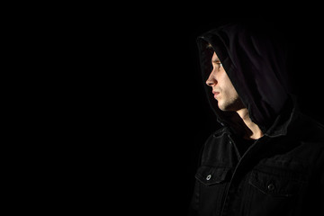 Fototapeta na wymiar Portrait of a young man in the hood black background
