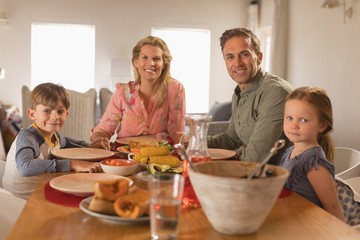 Happy family sitting on dining table at home