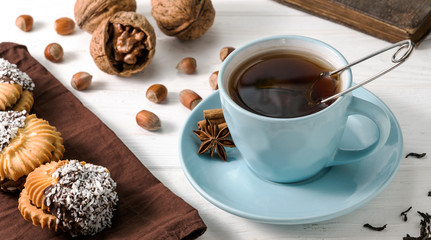 cup of tea with gingerbread and nuts on wooden white background.