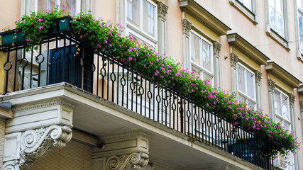 Fototapeta na wymiar Decotated balcony with flower pots. Pots of pink petunias. Floral design of balcony. Decorated exterior