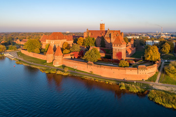 Medieval Malbork (Marienburg) Castle in Poland, main fortress of the Teutonic Knights at the Nogat river. Aerial view in fall in sunset light.