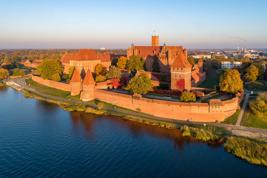 Medieval Malbork (Marienburg) Castle in Poland, main fortress of the Teutonic Knights at the Nogat river. Aerial view in fall in sunset light.