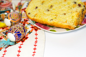 Easter cake near painted decorated eggs isolated on white background and embroidered towel. Copy space, top view. Traditions of celebrating spring holidays in Ukraine.
