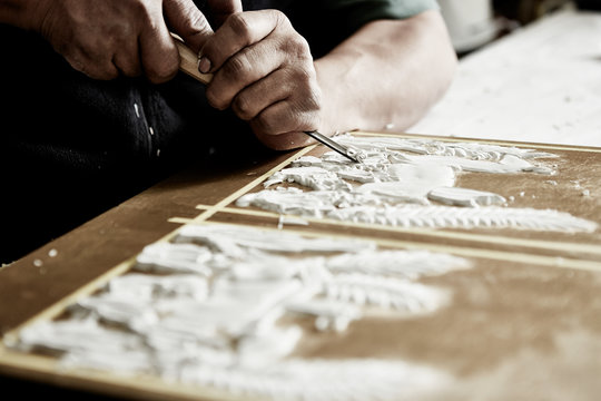 craftsman hands using a gouge to make an intricate carving