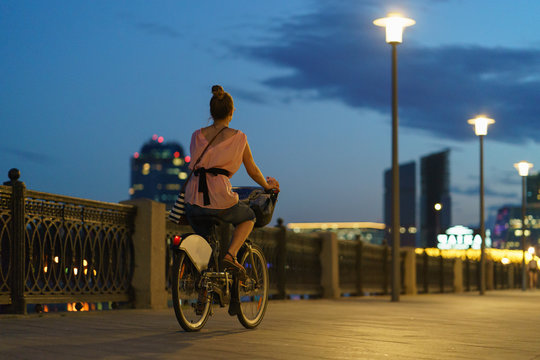 Biker on the embankment at the night time. Image with defocused background