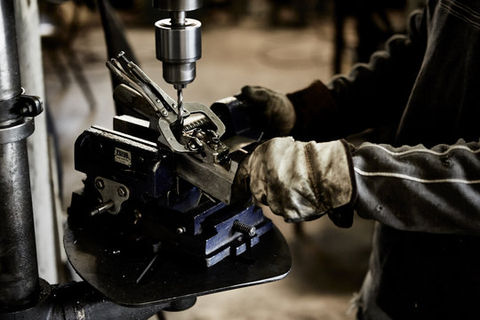 worker wearing heavy gloves using drill press