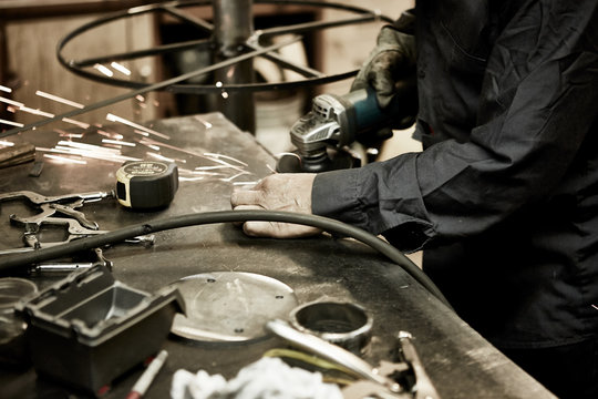 worker grinding metal in workshop