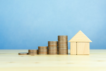 Coins stack and wooden house, save money for buy a house concept with copy space