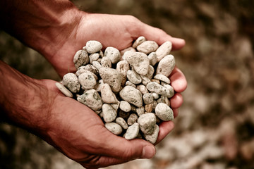 male hands holding stones for denim stone washing
