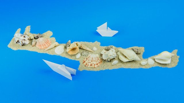 Paper boats off the coast of Crete. The map is lined with sand, with seashells lying on top.