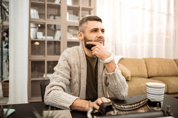 Thoughtful bearded man touching his chin in doubting gesture