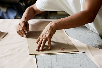 Hispanic man using pattern to cut leather