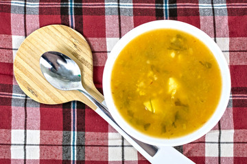 Delicious homemade soup, on checkered tablecloth.