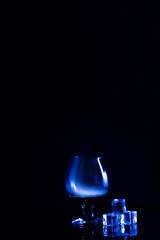 Two glasses for alcohol on a black background with a blue highlight