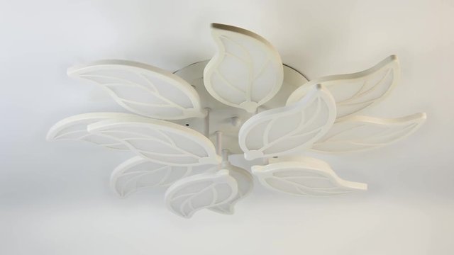 Modern LED chandelier in the shape of leaves on a white stretch ceiling 