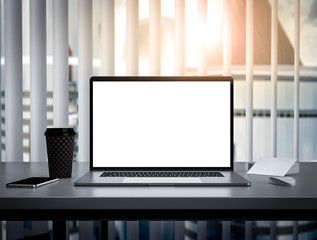 Laptop with blank screen on table in skyscraper office interior building - mockup, template