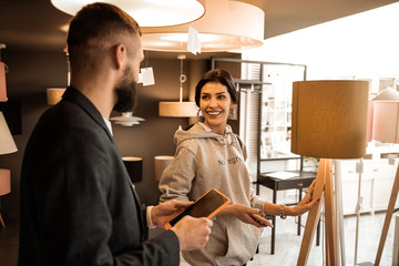 Obraz premium Beautiful dark-haired lady standing in grey hoodie and touching tall lamp
