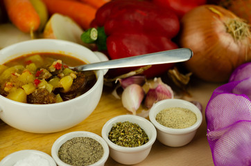 Traditional Hungarian goulash with beef, potatoes, tomatoes and peppers, a tasty dish in a white bowl