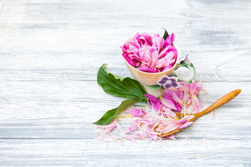Fototapeta na wymiar Cup of green tea and spring peonies blossom on a old wooden background. Rustic.