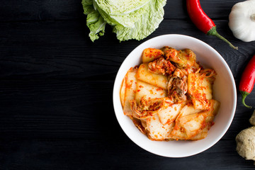 Kimchi in the white plate and ingredients on the black wooden  background.Top view.Copy space.
