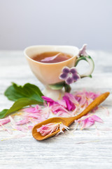 Cup of green tea and spring peonies blossom on a old wooden background. Rustic.