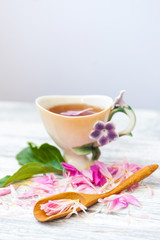 Cup of green tea and spring peonies blossom on a old wooden background. Rustic.