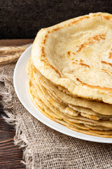 Stack of homemade pancakes blini on wooden background. Russian Maslenitsa, Shrove tide, pancake week, carnival, pancake day.