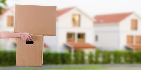 hand with cardboard boxes and houses, concept of moving and transport