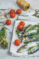 Sardines or baltic herring with tomatoes and rosemary on paper