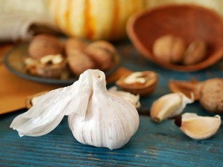 Garlic, walnuts, vegetables on a wooden table, ingredients for preparing healthy food, seasonal, organic, vegetarian cuisine