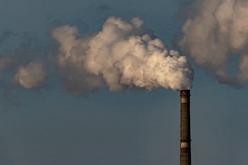 The pipe with white smoke. Industrial landscape. The smoke pollutes the environment