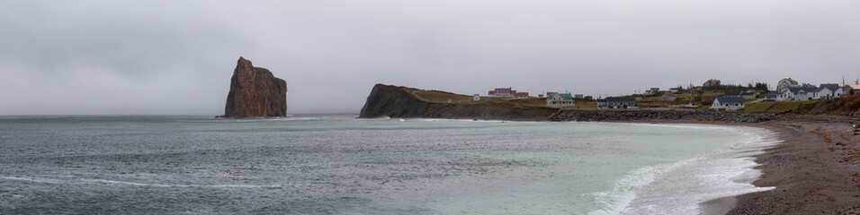 Panoramic view of a Rocky Coast on the Atlantic Ocean during a cloudy day. Taken in Perce, Quebec, Canada.
