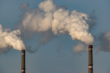Two pipes with white smoke. Industrial landscape. The smoke pollutes the environment