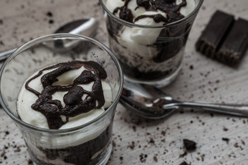 Homemade yogurt of crushed cookies, chocolate and cream with crumbs on the wooden table
