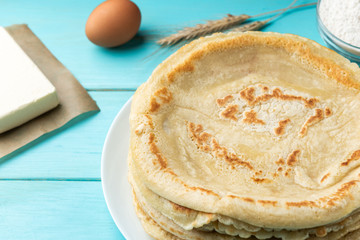 Homemade pancakes blini with flour, eggs and butter on blue wooden background. Russian Maslenitsa, Shrove tide, pancake week, carnival, pancake day.