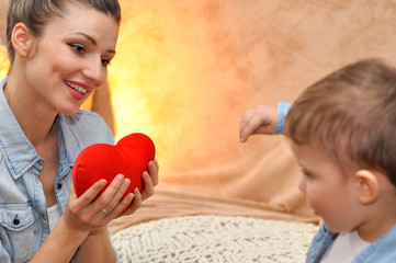 A little boy son gives a red heart to his beloved mother.