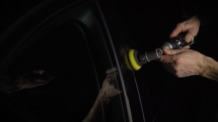 Naklejka premium Car detailing - Hands with orbital polisher in auto repair shop. Selective focus.