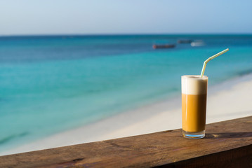 cappuccinoin glass on wooden table with sea view on tropical island