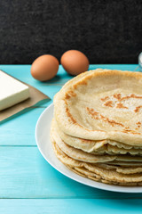 Homemade pancakes blini with flour, eggs and butter on blue wooden background. Russian Maslenitsa, Shrove tide, pancake week, carnival, pancake day.