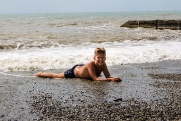 boy teenager lies on the seashore his washes sea foam and waves