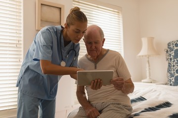 Fototapeta premium Female doctor and senior man using digital tablet