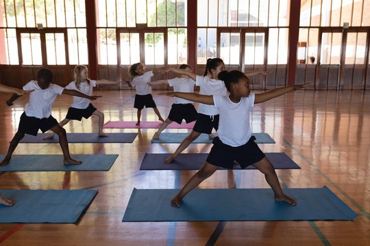 Schoolkids doing yoga on a yoga mat in school
